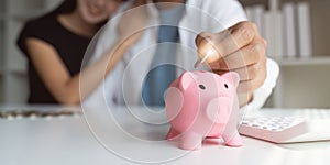 Man and woman couple smiling confident insert coin on piggy bank at home