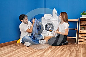 Man and woman couple smiling confident playing with cleaning clothes at laundry room