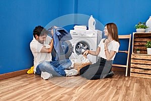 Man and woman couple smiling confident playing with cleaning clothes at laundry room