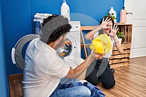 Man and woman couple smiling confident playing with cleaning clothes at laundry room