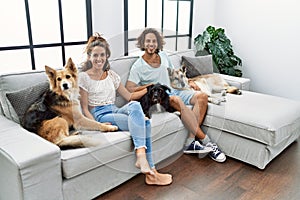 Man and woman couple smiling confident sitting on sofa with dogs at home