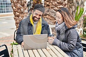 Man and woman couple using laptop drinking coffee at coffee shop terrace