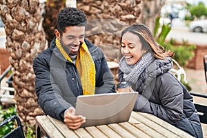 Man and woman couple using laptop drinking coffee at coffee shop terrace