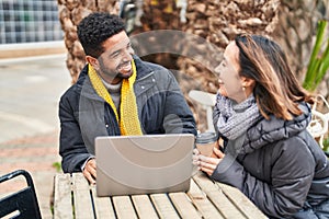 Man and woman couple using laptop drinking coffee at coffee shop terrace