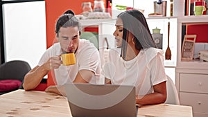 Man and woman couple using laptop drinking coffee at dinning room