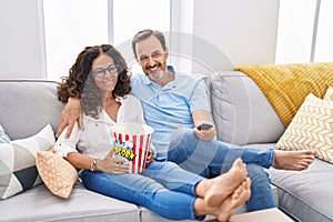 Man and woman couple watching movie sitting on sofa at home