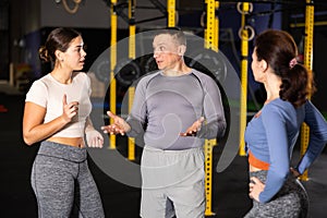 Man and woman crossfit trainers discussing training methods in gym