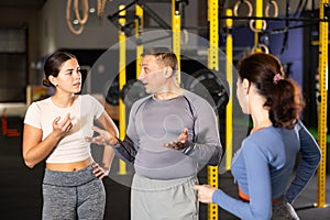 Man and woman crossfit trainers discussing training methods in gym