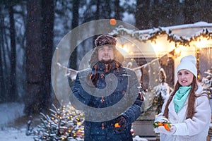 Man and woman cuddling in snowy forest. Adult couple in winter warm clothes have fun on walk. Romantic date, love story in winter