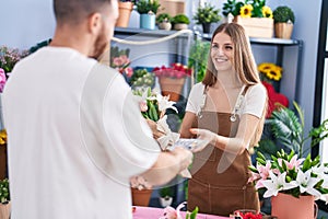 Man and woman customer paying for boquet of flowers at flower shop