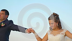 Man and woman are dancing against sky holding each other hands against the sky. Boy and girl in love are having fun