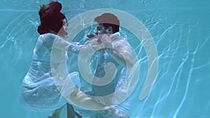 Man and a woman are dancing underwater.