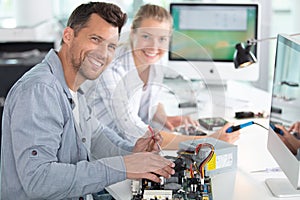 man and woman at desk repairing computer motherboard