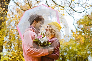 Man and woman of different ethnicity hugging in fall