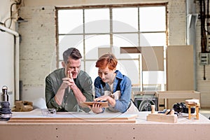 man and woman with digital tablet working together cooperating in workshop