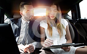Man and woman discussing work documents in taxi