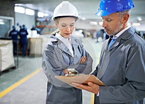 Man, woman and discussion with clipboard in factory for quality inspection or safety checks and process monitoring. Team