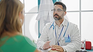 Man and woman doctor having medical consultation speaking with patient at the clinic