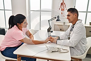 Man and woman doctor and patient having medical consultation with hands together at clinic