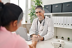 Man and woman doctor and patient having medical consultation with hands together at clinic