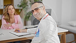 Man and woman doctor and patient having medical consultation smiling at the clinic