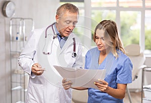 Man and woman doctors discussing diagnosis of patient in medical office