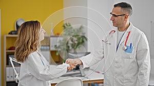 Man and woman doctors speaking and agreeing with handshake at the clinic