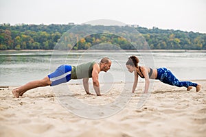 Man and woman doing push-ups on sand