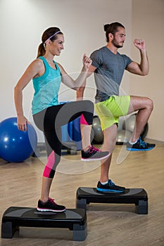 Man and woman doing step aerobic exercise on stepper