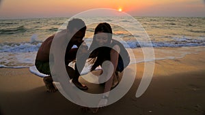 Man and woman draw on the sand heart