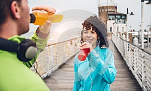 Man and woman drinking energy drink from bottle after fitness sport exercise