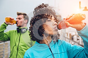 Man and woman drinking energy drink from bottle after fitness sport exercise