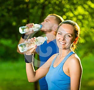 Man and woman drinking water from bottle after