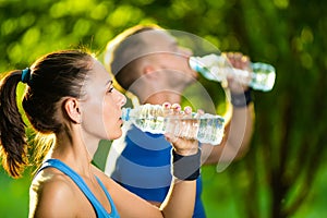 Man and woman drinking water from bottle after