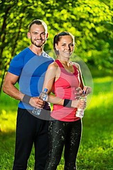 Man and woman drinking water from bottle after