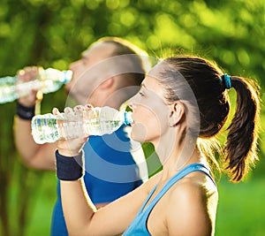 Man and woman drinking water from bottle after