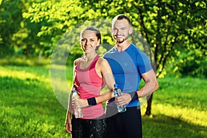 Man and woman drinking water from bottle after