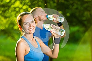 Man and woman drinking water from bottle after fitness sport exercise