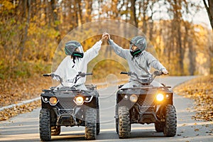 Man and woman driving quad bikes in autumn forest