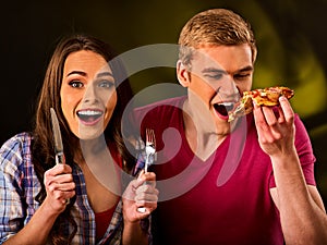 Man and woman eat slice pizza with knife and fork .
