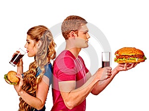 Man and woman eating big sandwich with cola