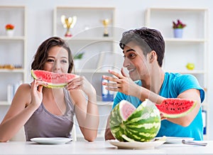 Man and woman eating watermelon at home