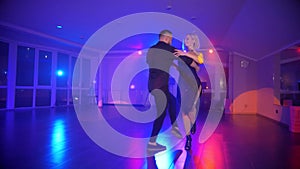 A man and woman elegantly tangoing at a lively party. Two dancers caught in the passion of the kizomba.