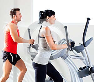 Man and woman with elliptical cross trainer at gym photo