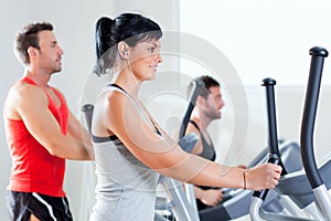 Man and woman with elliptical cross trainer at gym photo