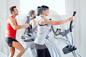 Man and woman with elliptical cross trainer at gym photo