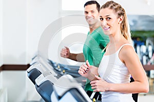 Man and woman on elliptical trainer in gym