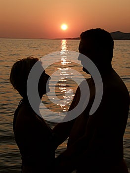 Man and woman embracing in the sea sunset