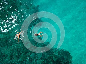 Man and woman enjoy a tropical vacation, swimming, diving, snorkeling together. Birds eye view from high above, drone picture. Gre