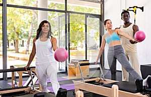 Man and woman exercising with ball at pilates lesson